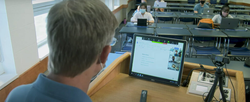 Instructor teaching students in a classroom and online
