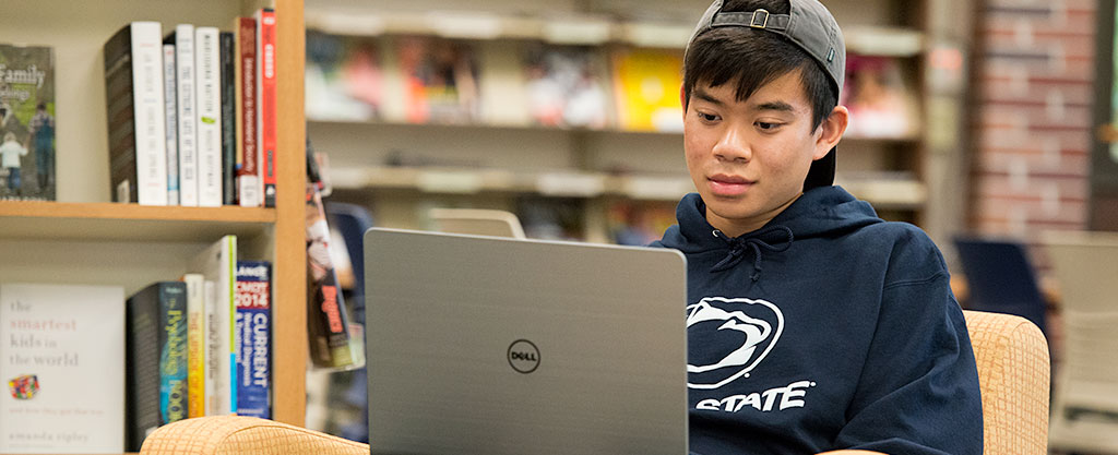 Penn State student with laptop in the library